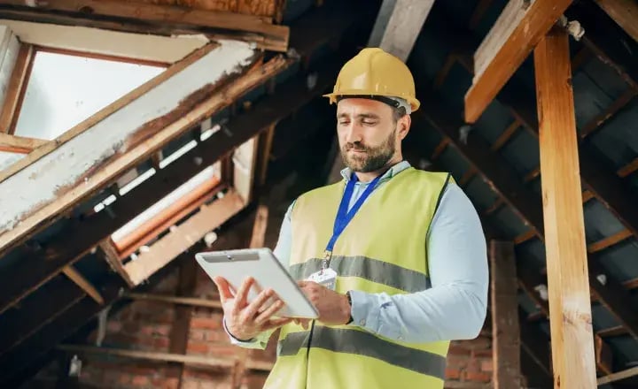 Worker with clipboard in attic. 