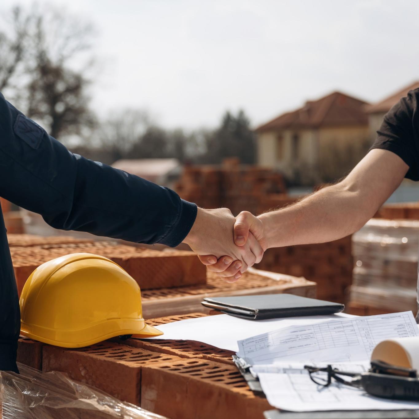 Roofing contractor and homeowner handshake agreement on construction site